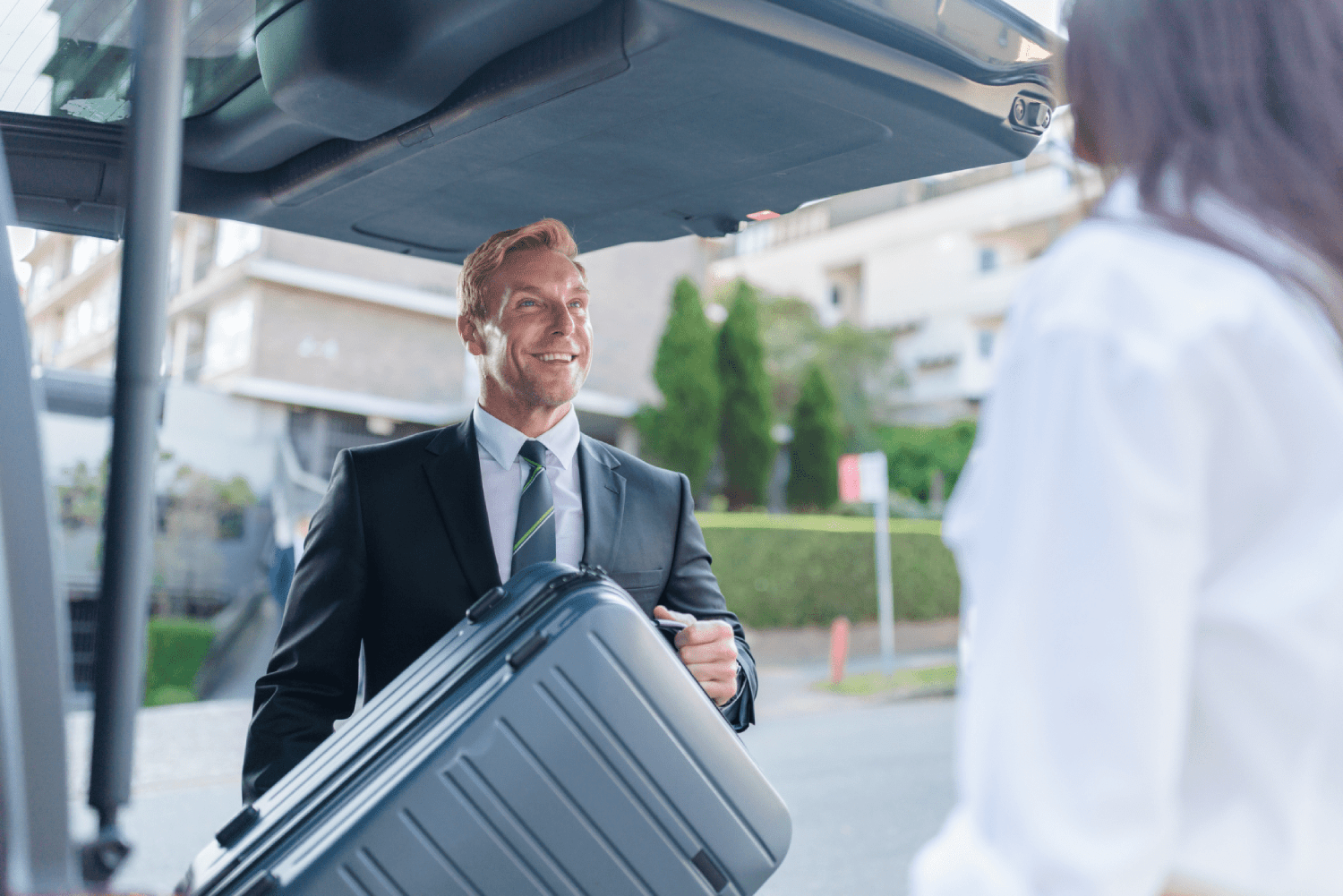 Professional Chauffeur assisting passenger with bags - Car Australia